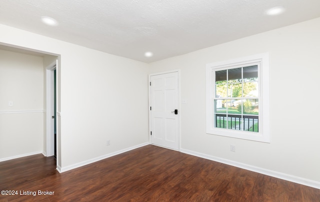 empty room featuring a textured ceiling and dark hardwood / wood-style flooring