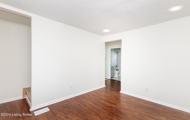 empty room with dark wood-type flooring and a textured ceiling