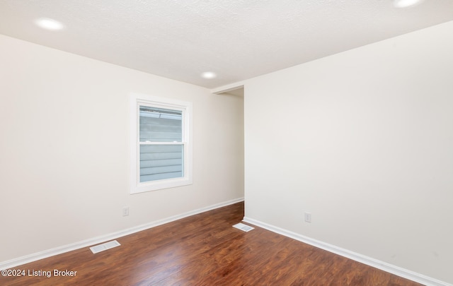 spare room with dark wood-type flooring and a textured ceiling