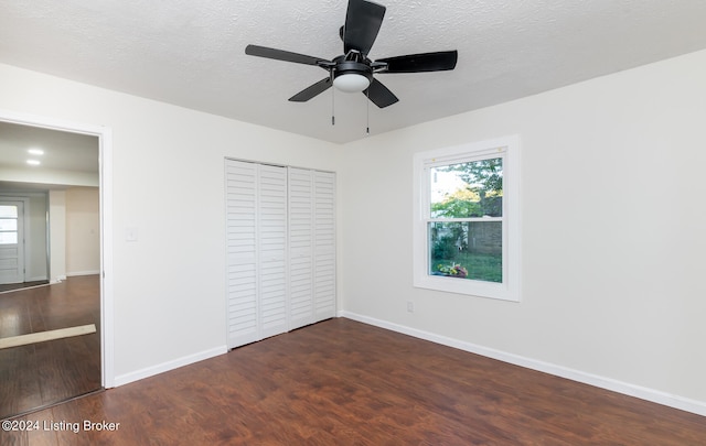 unfurnished bedroom featuring ceiling fan, a textured ceiling, a closet, and dark hardwood / wood-style flooring