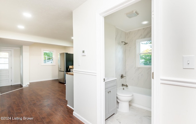 full bathroom with tiled shower / bath combo, vanity, hardwood / wood-style flooring, and a healthy amount of sunlight