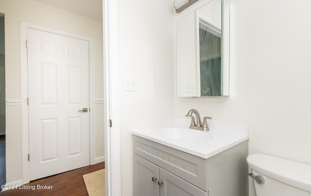 bathroom with hardwood / wood-style floors, vanity, and toilet