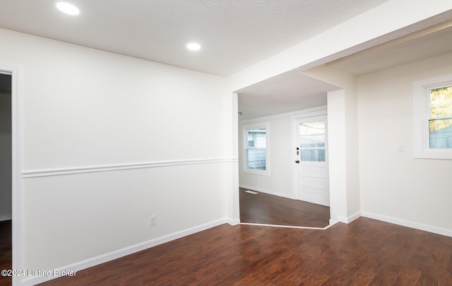 unfurnished room featuring dark wood-type flooring and a textured ceiling