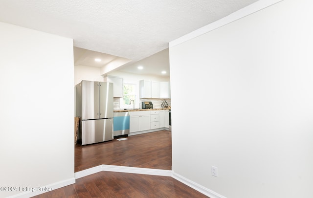 kitchen featuring stainless steel appliances, white cabinetry, a textured ceiling, dark hardwood / wood-style floors, and decorative backsplash