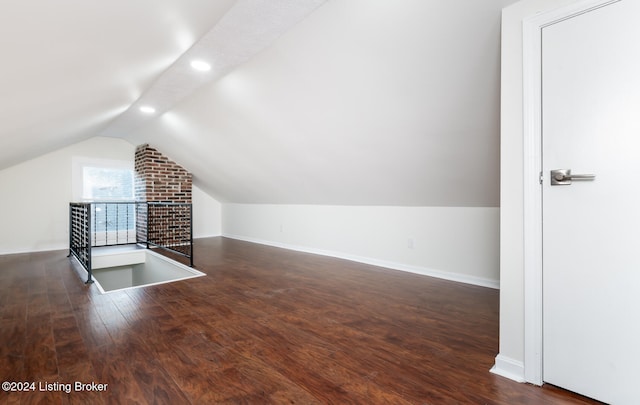 additional living space featuring dark wood-type flooring and vaulted ceiling