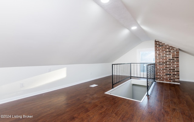 additional living space featuring dark wood-type flooring and lofted ceiling