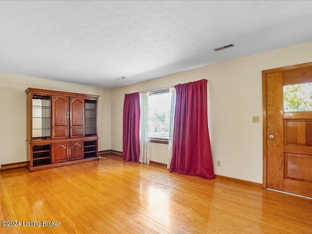 unfurnished living room featuring a textured ceiling, light hardwood / wood-style flooring, and plenty of natural light