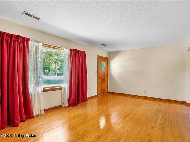 spare room with a textured ceiling and wood-type flooring