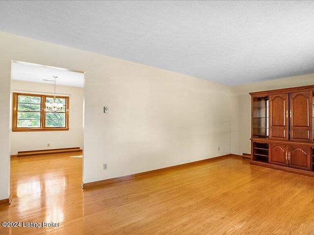 unfurnished living room featuring light hardwood / wood-style floors, a notable chandelier, and a textured ceiling