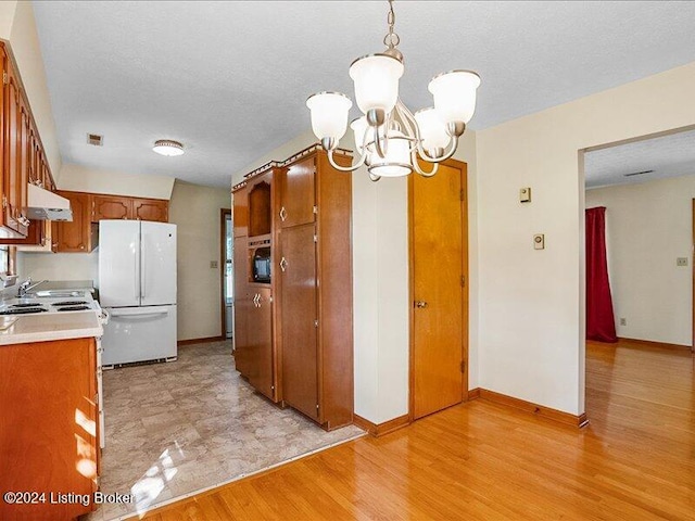 kitchen featuring a textured ceiling, pendant lighting, white fridge, a notable chandelier, and light hardwood / wood-style flooring