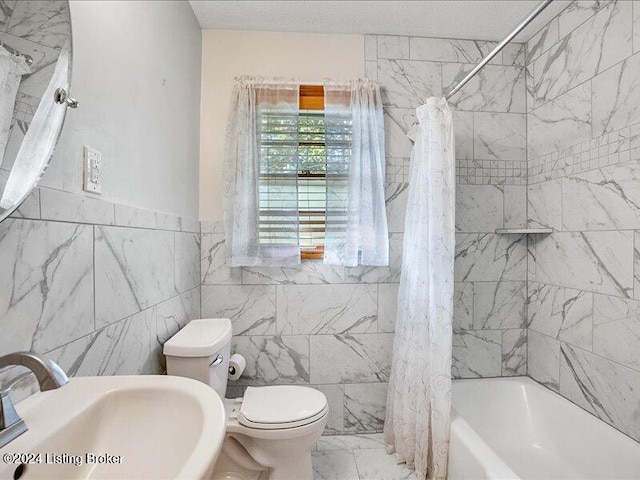 full bathroom with sink, shower / tub combo, a textured ceiling, toilet, and tile walls