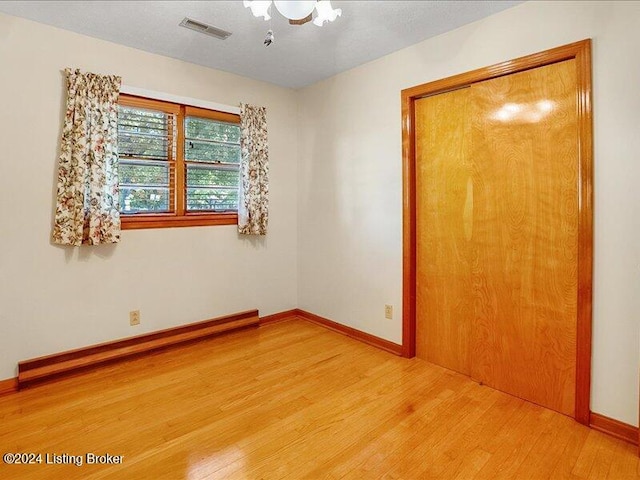 unfurnished bedroom featuring a baseboard heating unit and light hardwood / wood-style floors