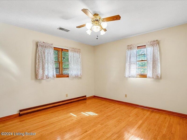 spare room featuring a baseboard heating unit, hardwood / wood-style flooring, and ceiling fan