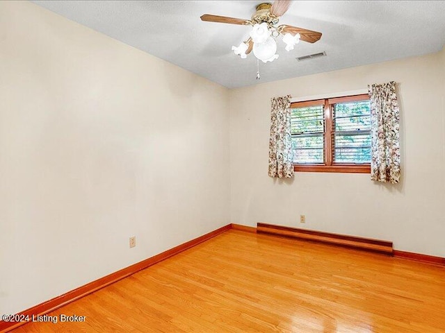 unfurnished room with a textured ceiling, hardwood / wood-style flooring, baseboard heating, and ceiling fan