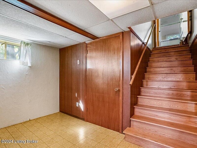 stairs featuring wood walls and a paneled ceiling