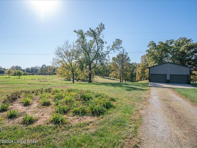 view of yard featuring a rural view, an outdoor structure, and a garage