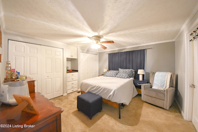 carpeted bedroom featuring crown molding, a textured ceiling, multiple closets, and ceiling fan