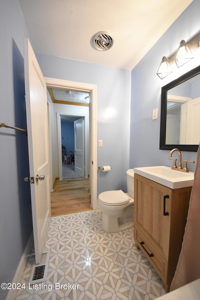 bathroom with vanity, toilet, and hardwood / wood-style flooring