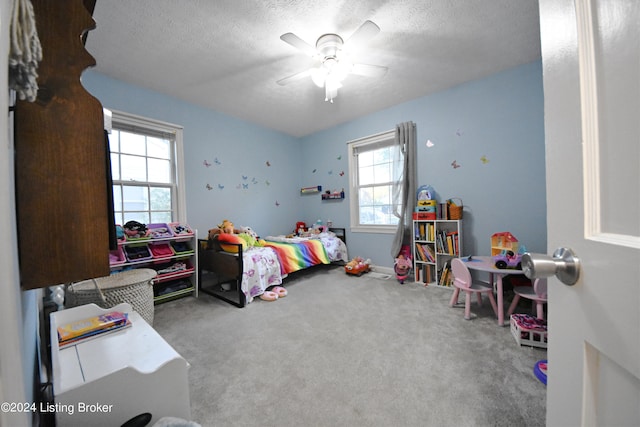 carpeted bedroom with a textured ceiling, multiple windows, and ceiling fan