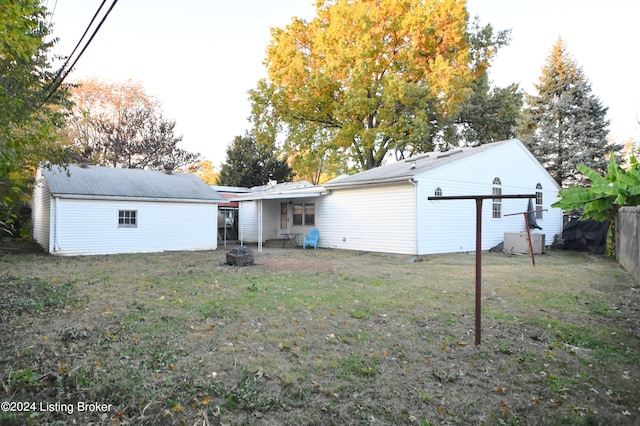 back of property with an outdoor fire pit and a lawn