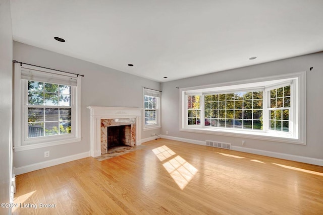 unfurnished living room featuring a premium fireplace and light hardwood / wood-style flooring