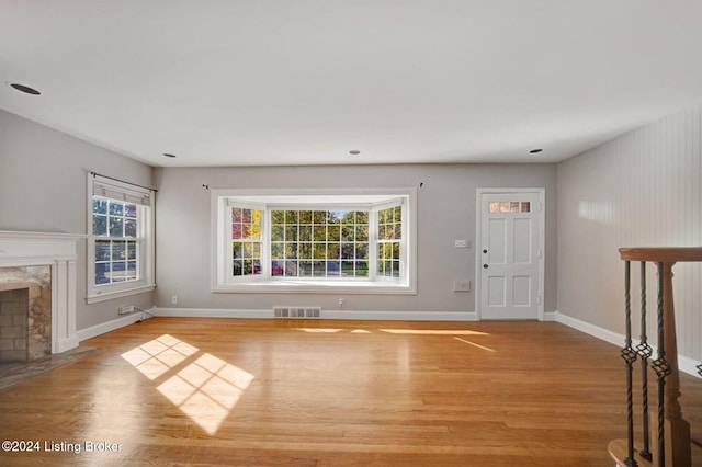 unfurnished living room with a fireplace, light wood-type flooring, and plenty of natural light