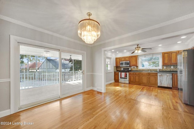 kitchen with appliances with stainless steel finishes, decorative backsplash, a healthy amount of sunlight, and light hardwood / wood-style floors