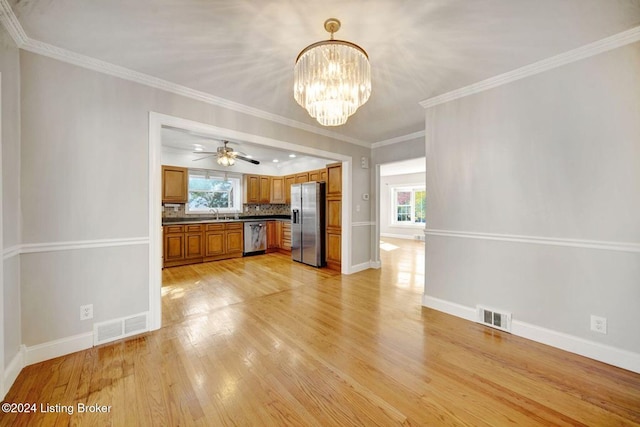 kitchen featuring appliances with stainless steel finishes, backsplash, hanging light fixtures, crown molding, and light hardwood / wood-style flooring