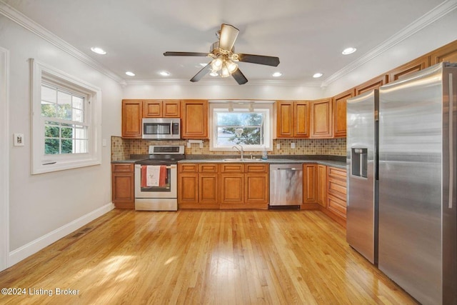 kitchen with light hardwood / wood-style flooring, ceiling fan, stainless steel appliances, and crown molding