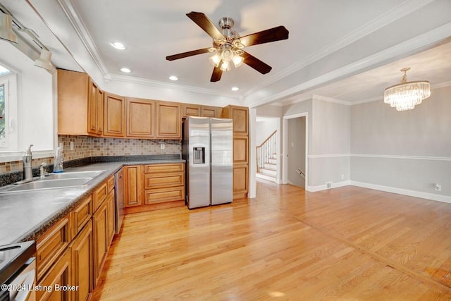 kitchen with tasteful backsplash, appliances with stainless steel finishes, hanging light fixtures, crown molding, and light hardwood / wood-style flooring