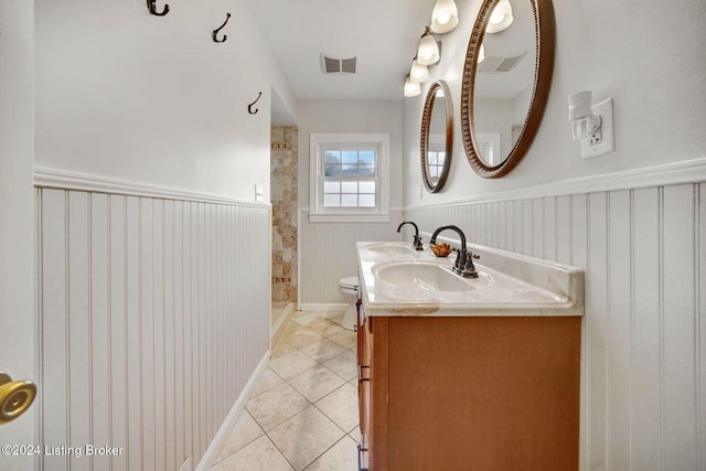 bathroom with toilet, vanity, a shower, and tile patterned flooring