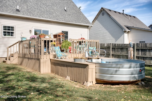 rear view of house featuring a hot tub, a wooden deck, and a yard