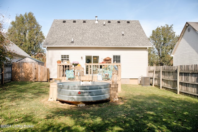 rear view of house with central AC, a shed, a yard, and a deck