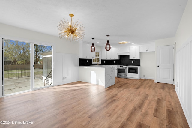 kitchen featuring tasteful backsplash, stainless steel range with electric cooktop, pendant lighting, white cabinets, and light hardwood / wood-style flooring