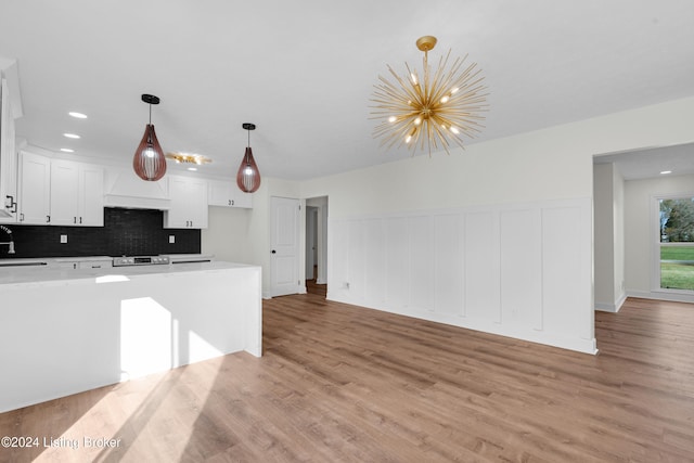 kitchen featuring white cabinetry, light wood-type flooring, pendant lighting, and backsplash