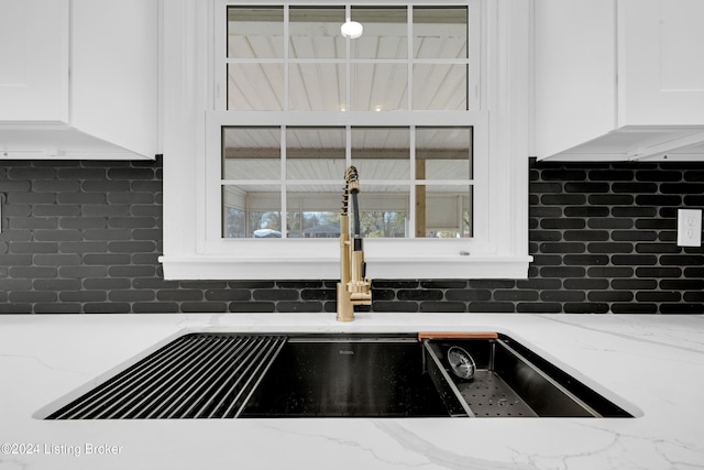 details with sink, white cabinetry, decorative backsplash, and light stone countertops