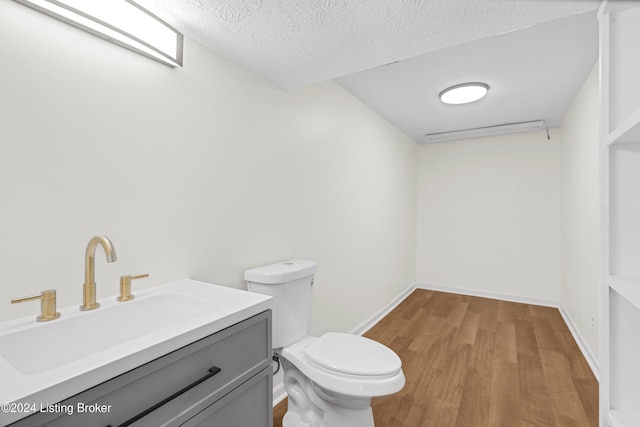 bathroom featuring wood-type flooring, a textured ceiling, toilet, and vanity