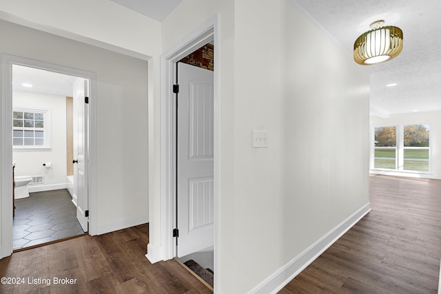 corridor with a textured ceiling and dark hardwood / wood-style flooring