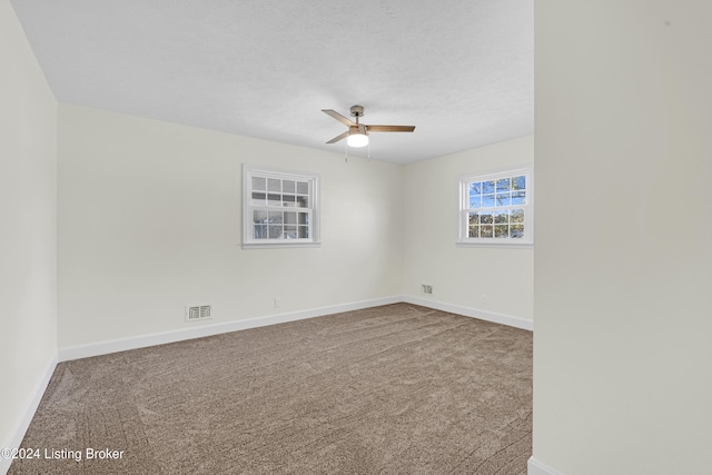 empty room with a textured ceiling, ceiling fan, and carpet floors