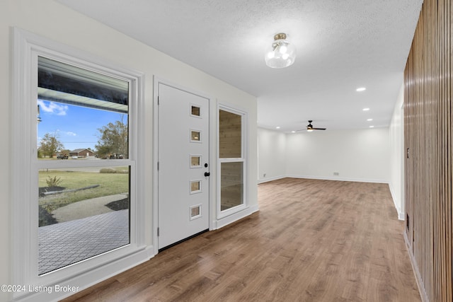 foyer entrance featuring light hardwood / wood-style floors, ceiling fan, and a textured ceiling