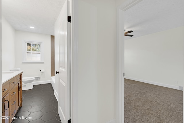 bathroom with a textured ceiling, vanity, ceiling fan, and toilet