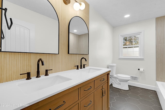 bathroom featuring toilet, vanity, a textured ceiling, and tile patterned floors