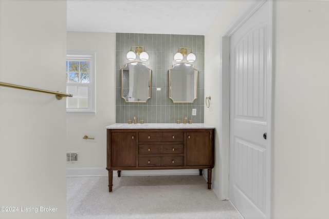 bathroom with tile walls, decorative backsplash, vanity, and a textured ceiling