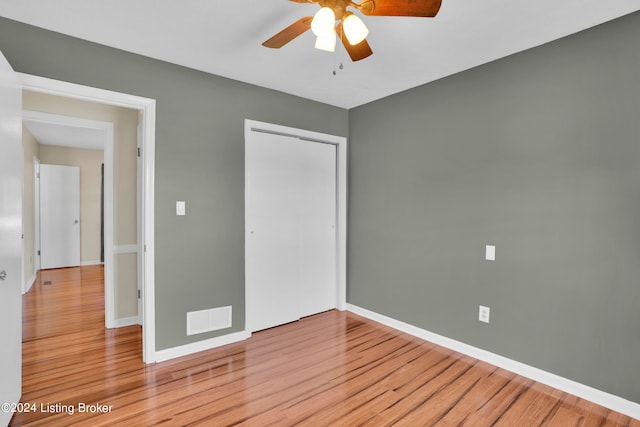 unfurnished bedroom with light hardwood / wood-style flooring, a closet, and ceiling fan