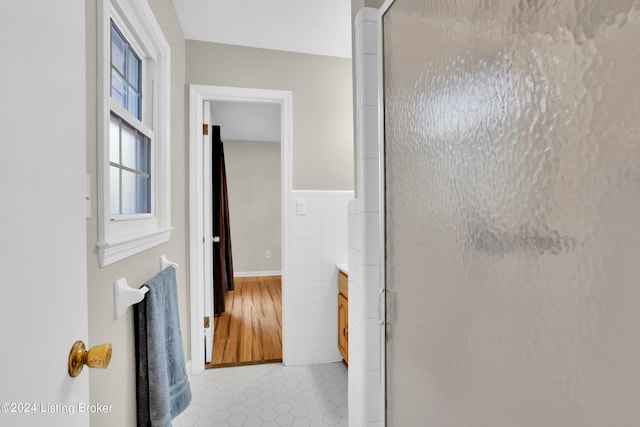 bathroom featuring vanity, tile walls, a shower with shower door, and hardwood / wood-style flooring