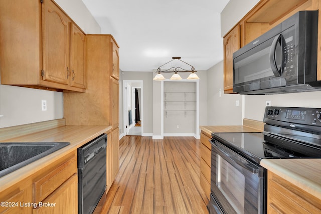 kitchen with black appliances, light hardwood / wood-style flooring, and decorative light fixtures