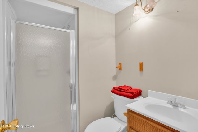 bathroom with vanity, toilet, a textured ceiling, and an enclosed shower