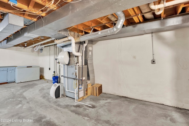 basement with heating unit and white refrigerator