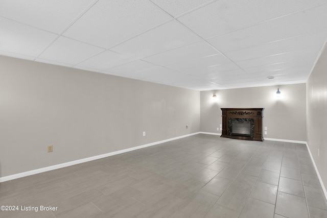 unfurnished living room featuring a drop ceiling and tile patterned flooring