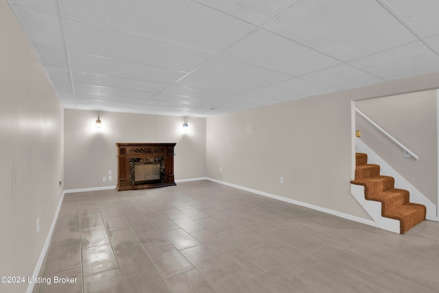 unfurnished living room featuring a paneled ceiling and tile patterned floors